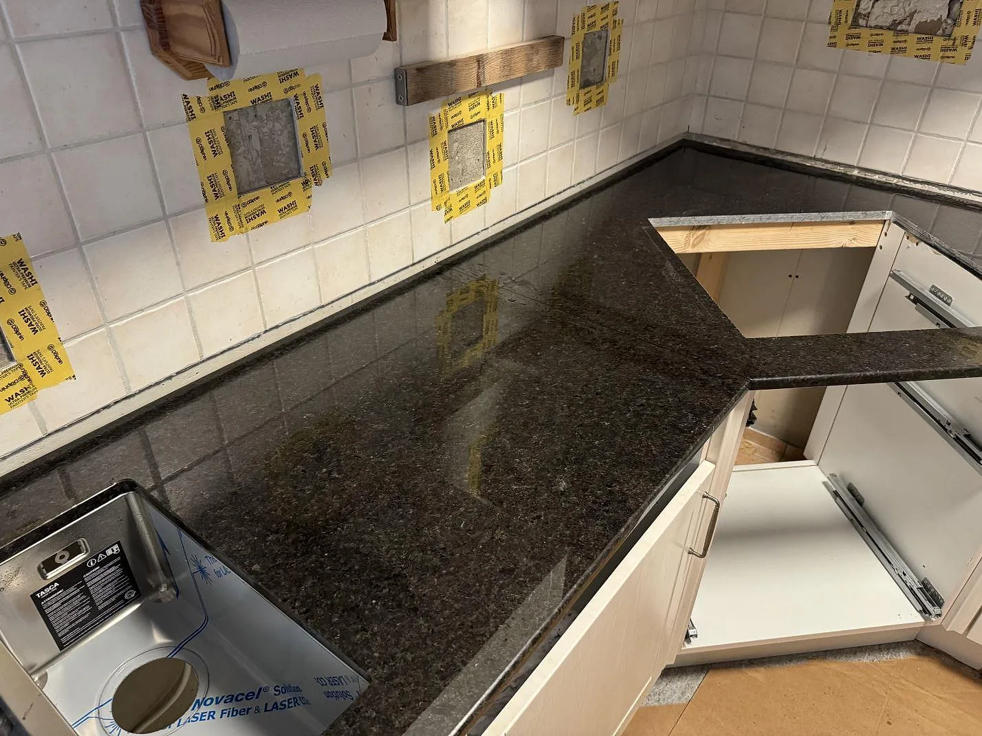 L-formad køkkenbordplade i Angola Black granit, poleret, med mørk stenyta og rektangulärt udskæring under montering i Malmö.