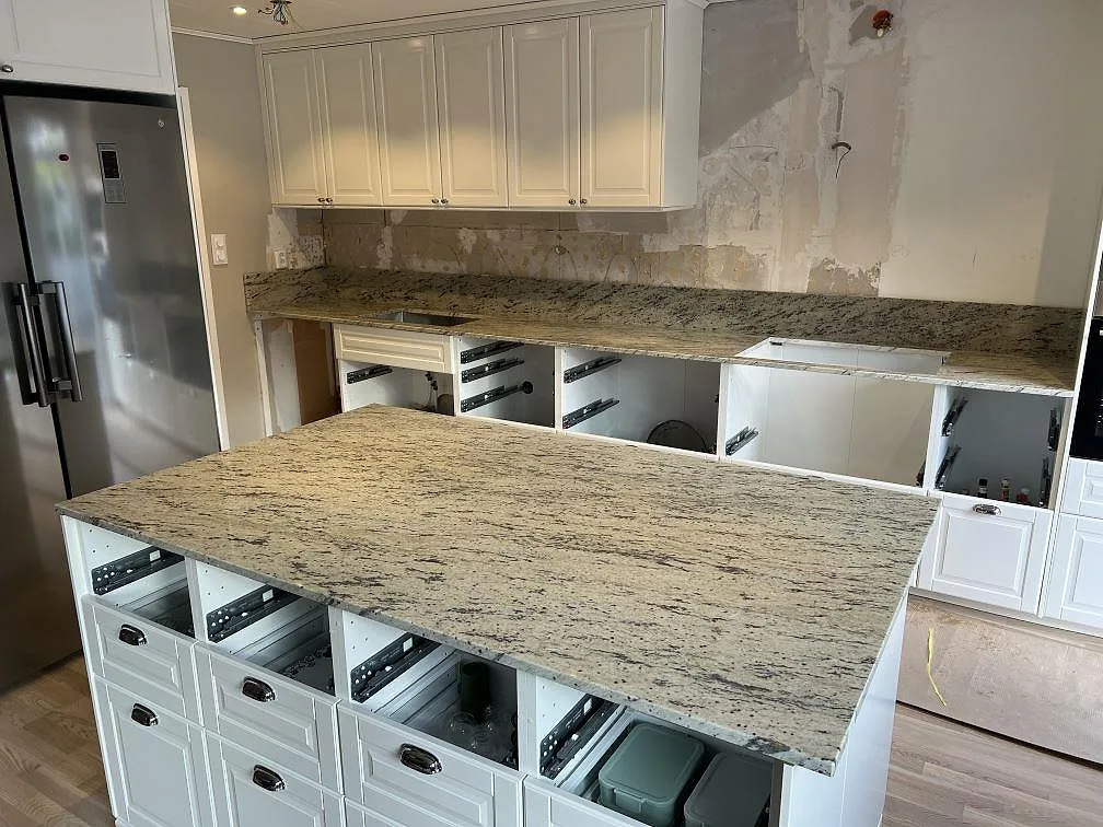 Køkkenbordplade og køkkenø i poleret Antique White granit, 20 mm, monterade i ett køkken i Järfälla.