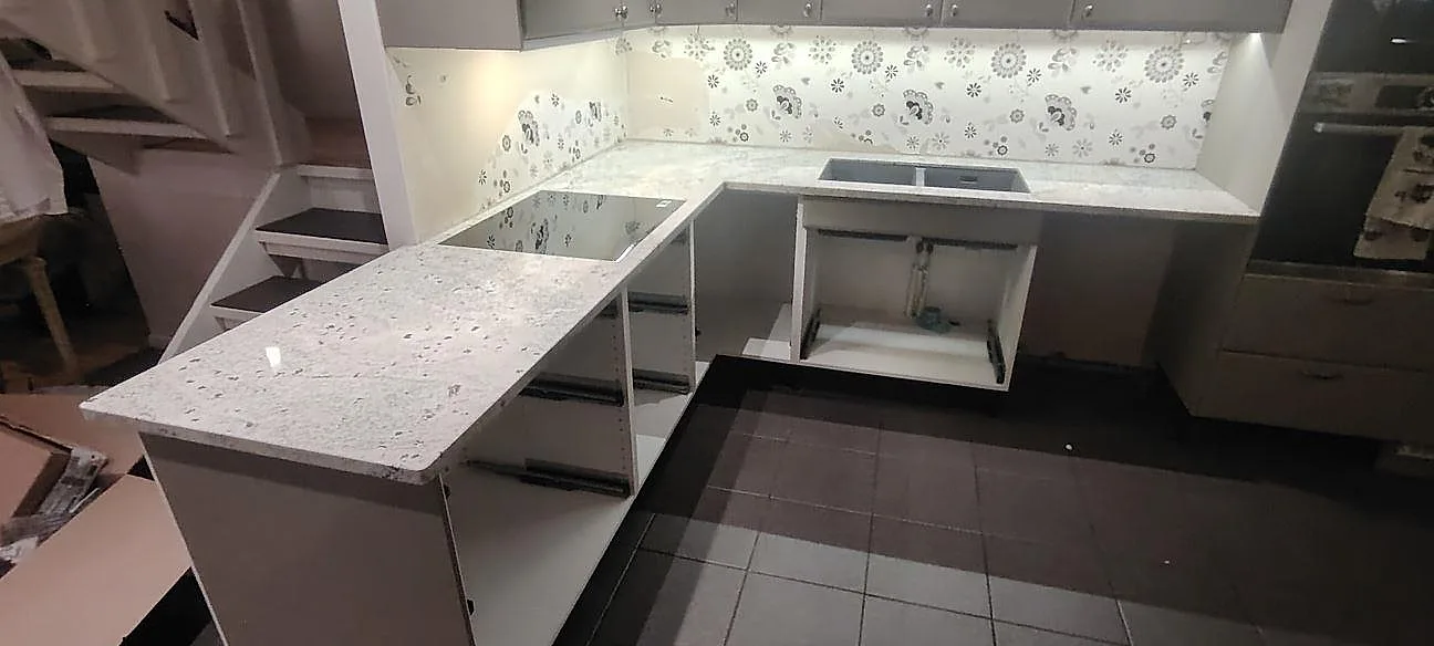 Køkkenbordplade i Antique White granit, poleret 30 mm, med bred retur i ett køkken under montering i Norrtälje.