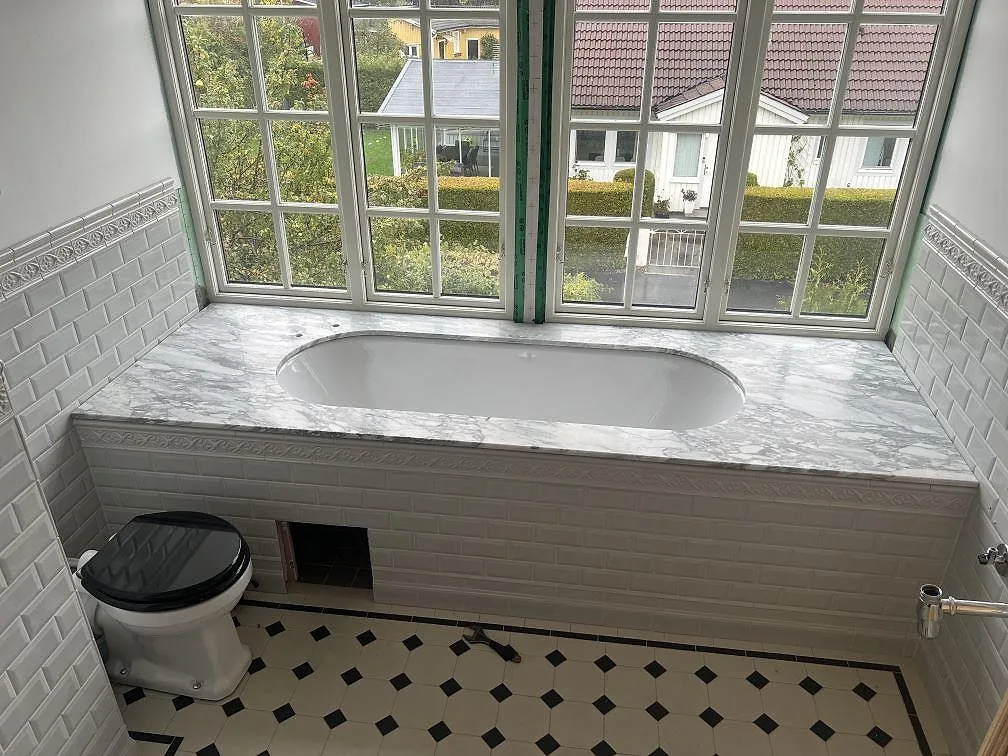 Badkarsomramning i mat 20 mm Arabescato marmor med grå åretegning rundt om ett inbyggt badkar i Södertälje.