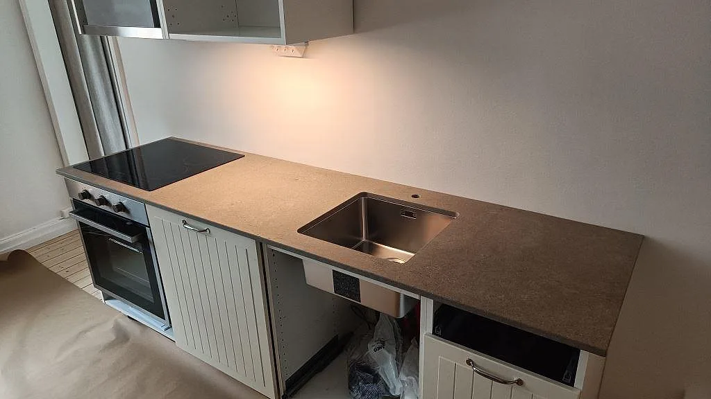 Køkkenbordplade i mat Azul Valverde marmor med rostfri vask og komfur längs en lige köksrad i Göteborg.