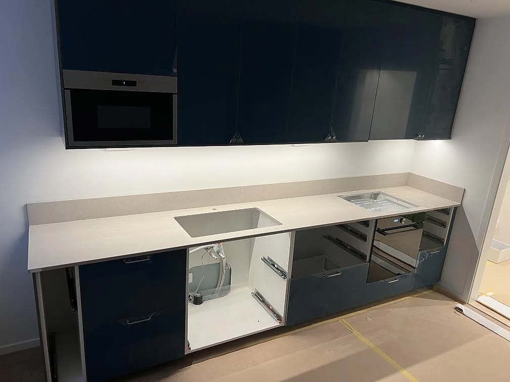 Køkkenbordplade i mat Azul Valverde marmor med låg stänkkant, diskhoöppning og hällzon i ett køkken i Hägersten.