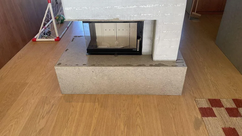 Eldstadsbeklädnad i mat Azul Valverde kalksten, 20 mm, monteret som sockel rundt om en kamin i Växjö.