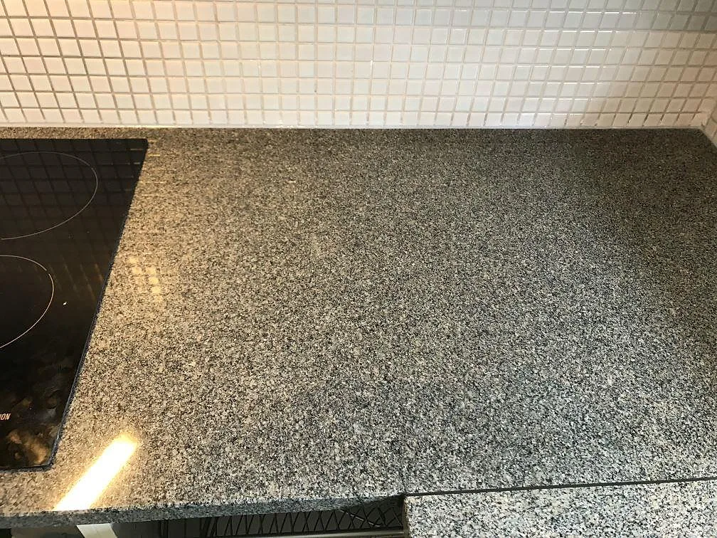 Køkkenbordplade i poleret Bohus Grå granit med stor underlimmad rostfri vask under fönstret i ett køkken i Malmö.