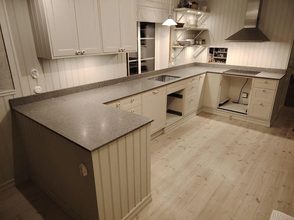 Køkkenbordplade i mat Bohus Grå granit, 20 mm, med L-formad arbetsyta og uppvikt stänkkant i ett køkken i Mockfjärd.