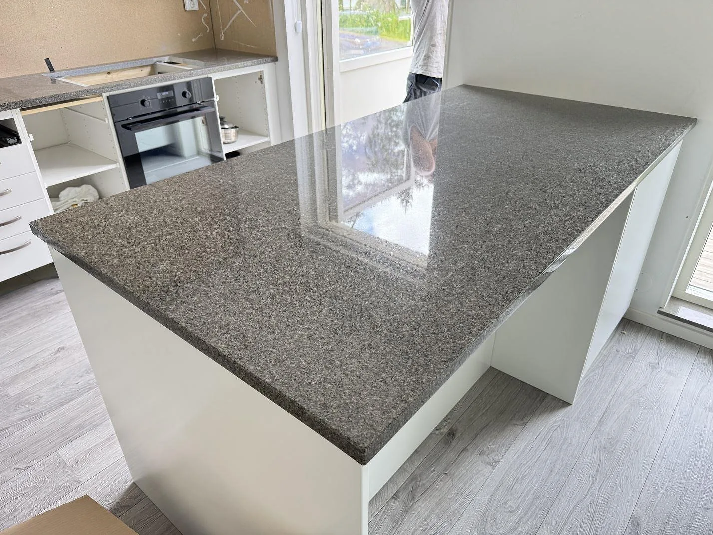 Køkkenø i poleret Bohus Grå granit, 30 mm, monteret i ett køkken i Tenhult med hvid köksinredning.