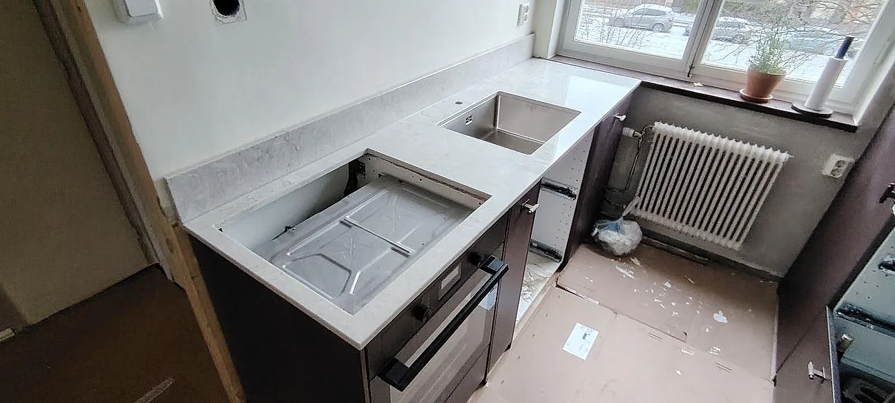 Køkkenbordplade i poleret Caesarstone Bianco Drift, lys kvartskomposit, med hällöppning, vask og låg stänkkant i Johanneshov.