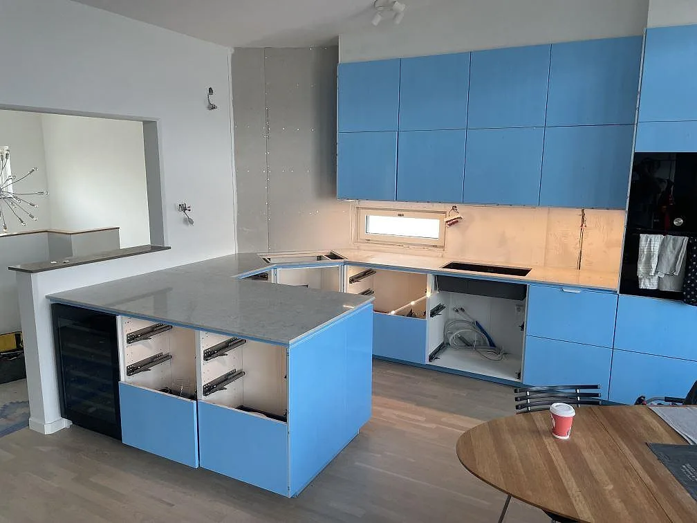Køkkenbordplade i 20 mm poleret Caesarstone Bianco Drift, komposit, med køkkenø og väggbänk i ett køkken i Lomma under montering.