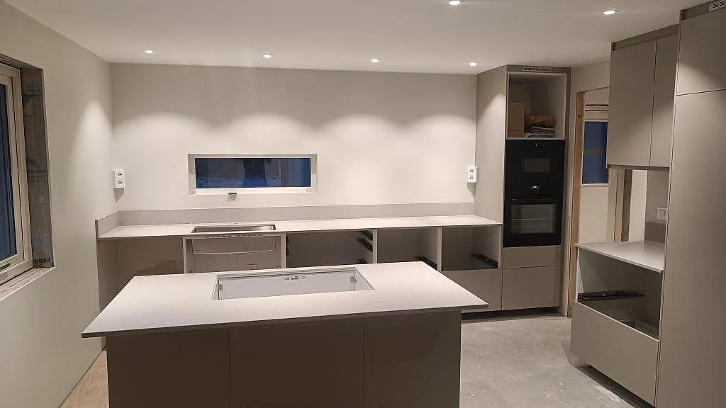 Køkkenbordplade i Caesarstone Clamshell, mat komposit, med køkkenø, hällöppning, stänkkant og vask i ett køkken i Åseda.