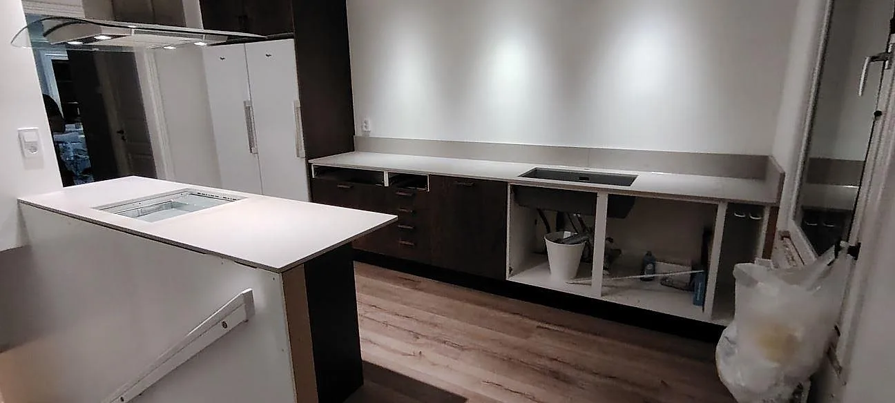 Mat køkkenbordplade i Caesarstone Clamshell, 20 mm komposit, på halvö og väggbänk i ett køkken i Gävle under montering.