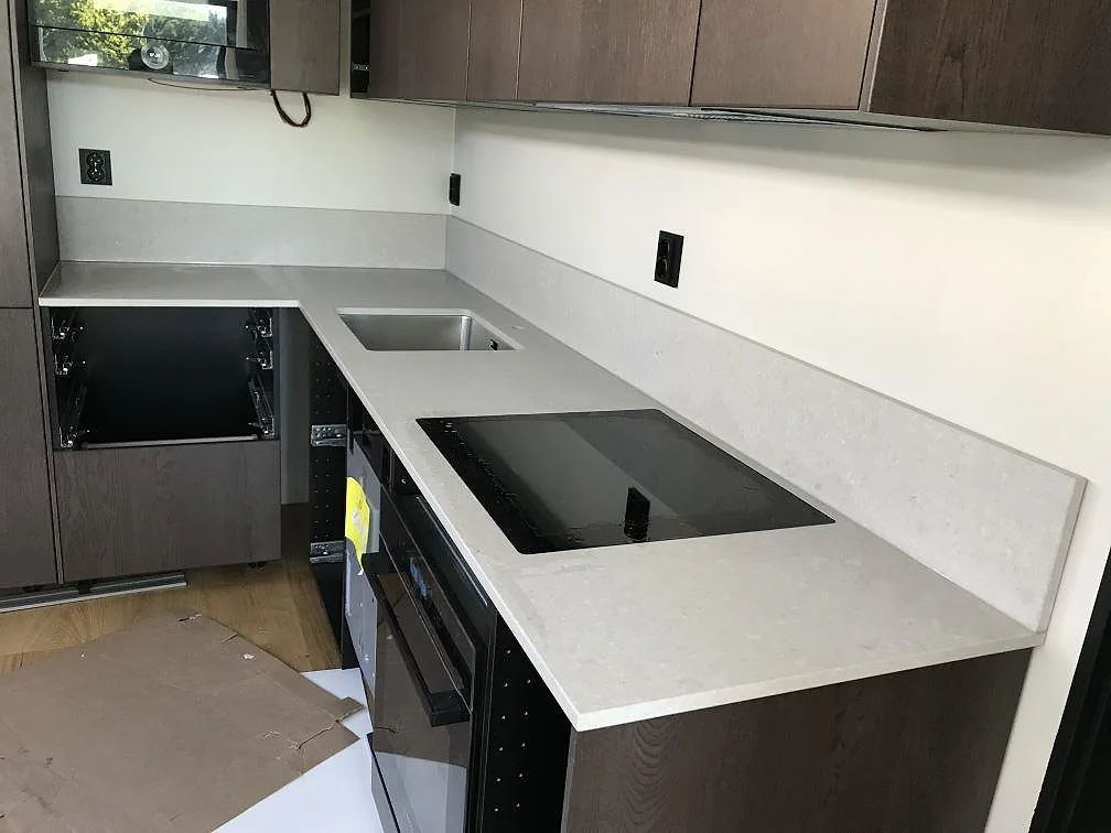 Køkkenbordplade i Caesarstone Clamshell, beige mat kvartskomposit, i ett L-format køkken med underlimmad rostfri vask og infälld induktionshäll i Göteborg.