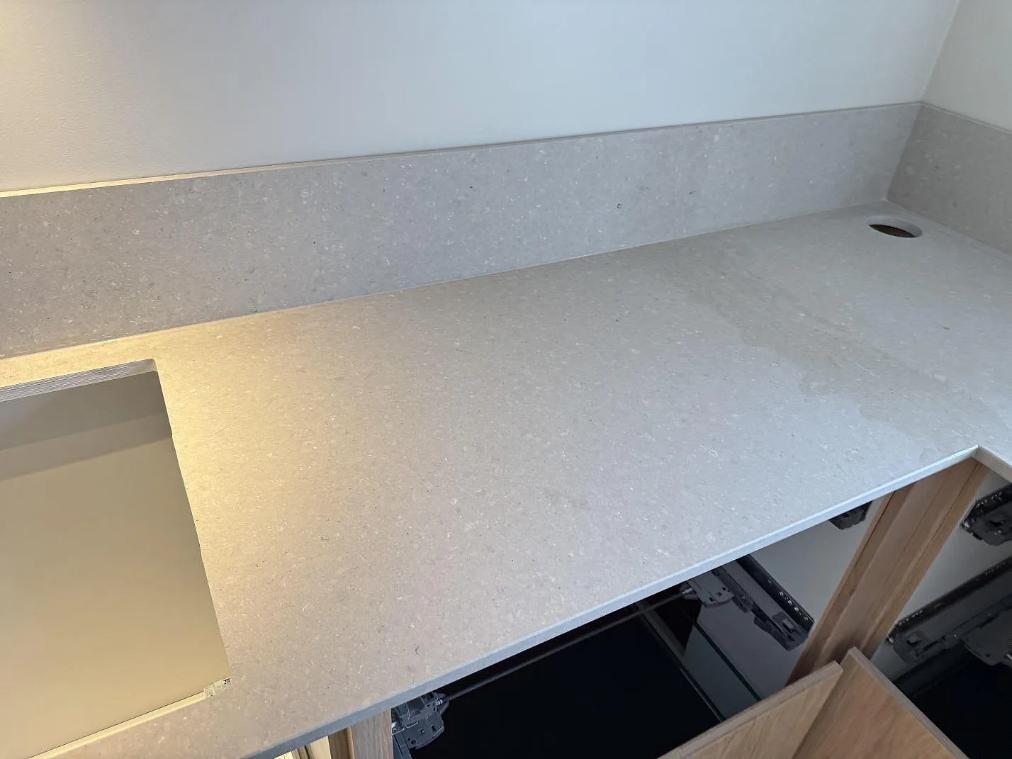 Bordplade i mat Caesarstone Clamshell komposit med stänkkant, rektangulär ursågning og rundt om armaturhål i ett badeværelse i Löddeköpinge.