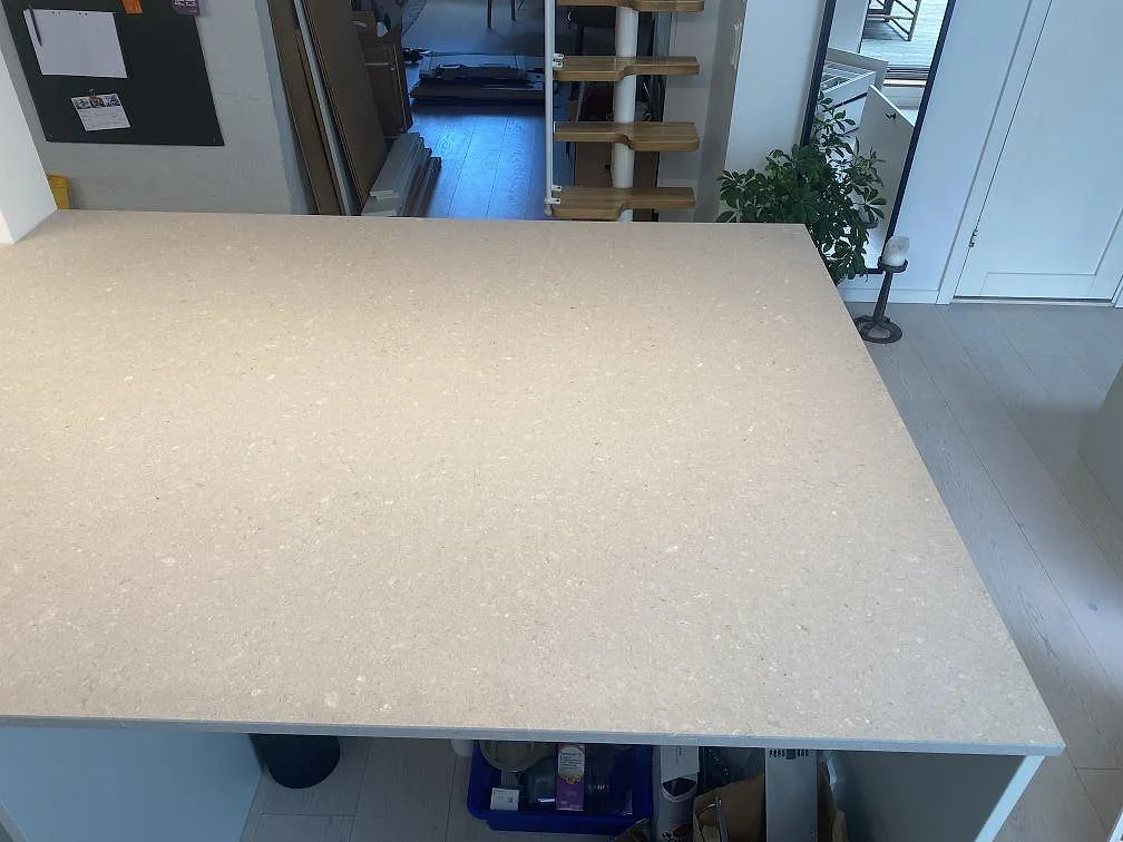 Køkkenbordplade og stor køkkenø i Caesarstone Clamshell, mat cremevit kvartskomposit, i ett ljust køkken i Malmö.