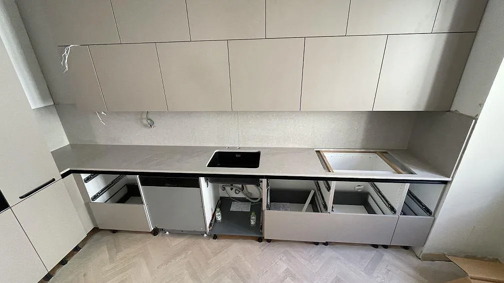 Lige køkkenbordplade i mat Caesarstone Clamshell komposit med stænkplade, sort vask og förberedd hällöppning i ett køkken i Malmö.