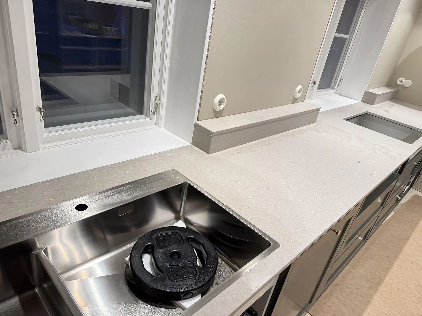 Køkkenbordplade i mat Caesarstone Clamshell kvartskomposit med rostfri vask, låg stänkkant og hällöppning i ett køkken i Osby.
