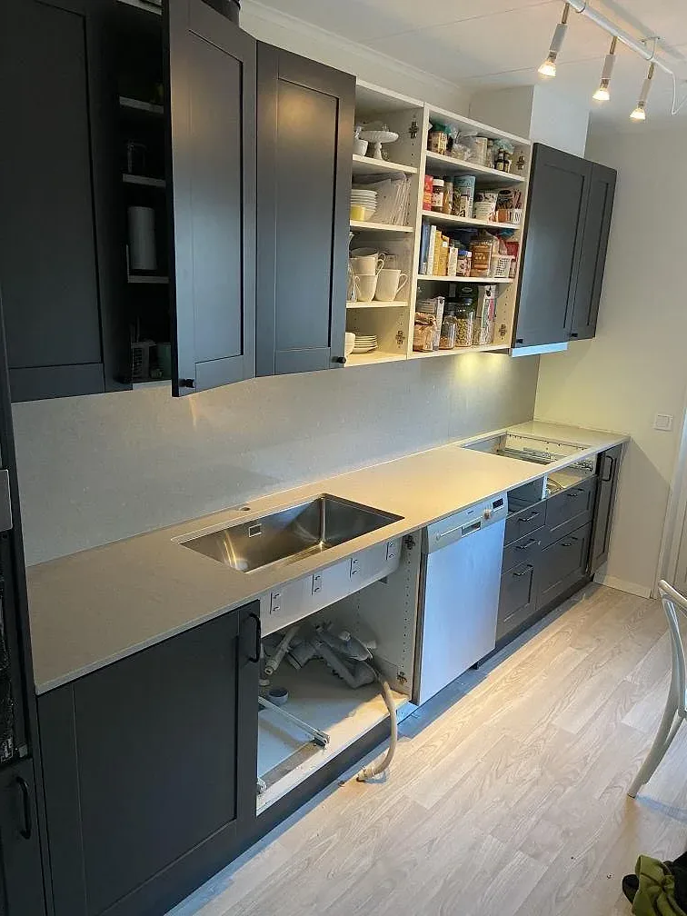 Køkkenbordplade i lys Caesarstone Clamshell, mat kvartskomposit, med underlimmad rostfri vask og öppna skabe i ett køkken i Växjö.