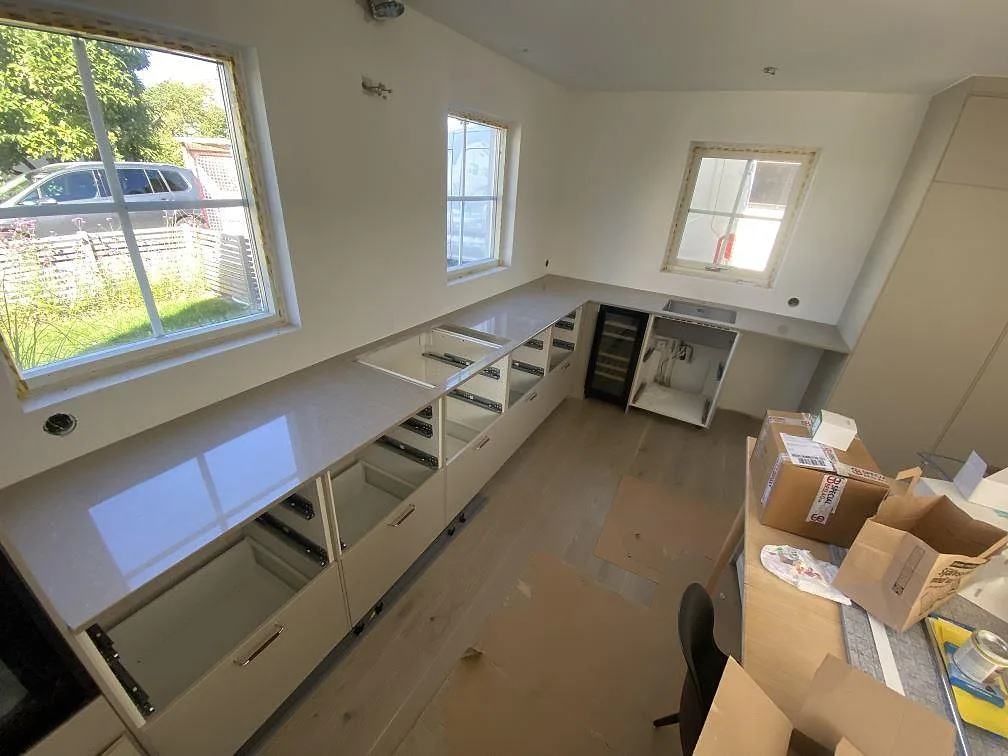 Køkkenbordplade i Caesarstone Shitake, poleret greige kvartskomposit, i ett L-format køkken under montering i Limhamn.