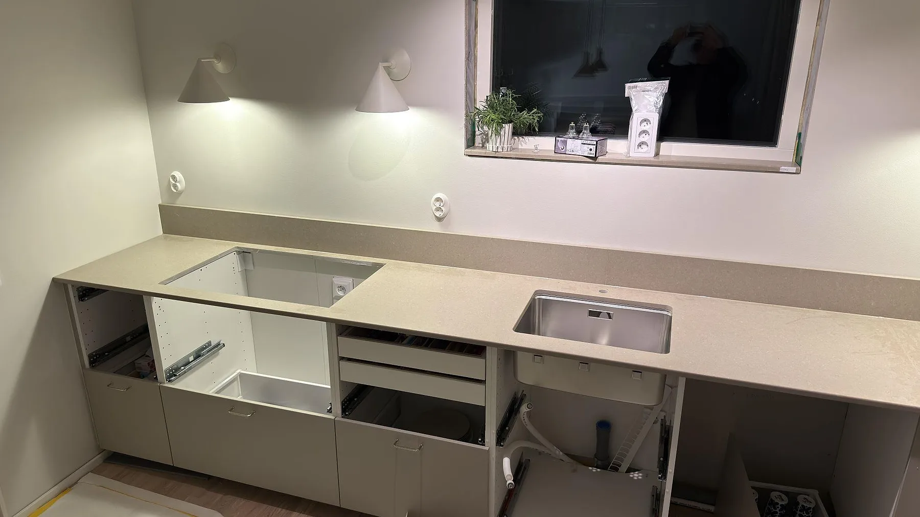 Køkkenbordplade i Caesarstone Shitake, mat taupebrun kvartskomposit, med underlimmad rostfri vask og udskæring for kogeplade längs en L-formad bordplade i ett køkken i Örebro.