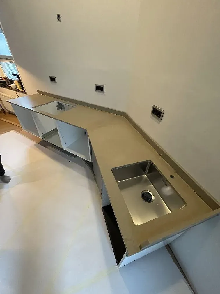 Køkkenbordplade i Caesarstone Shitake, mat, på en L-formad köksdel med underlimmad rostfri vask i ett køkken under montering i Stockholm.