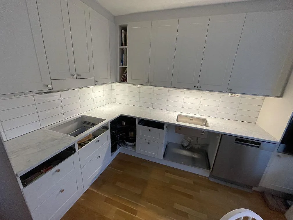 Køkkenbordplade i hvid Carrara C marmor, poleret, monteret i U-form i ett køkken i Bromma under montering med underlimmad rostfri vask og udskæring for induktionshäll.