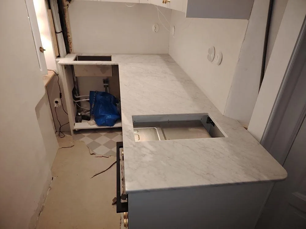 Køkkenbordplade i Carrara C marmor, mat 20 mm, med synliga udskæring under montering i ett køkken i Stockholm.