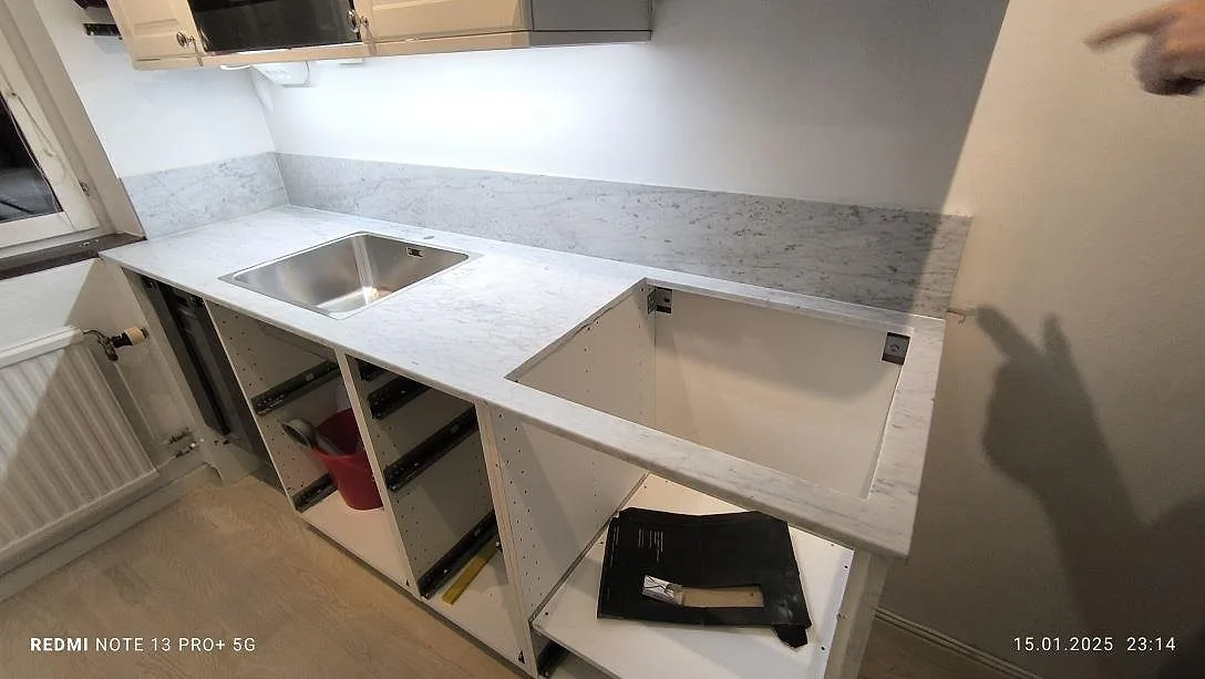 Køkkenbordplade i mat Carrara C, hvid marmor med vask, hällöppning og låg stänkkant under montering i Årsta.