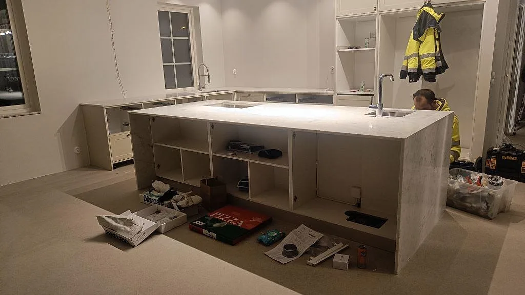 Køkkenbordplade og stor køkkenø i Carrara CD marmor, poleret, i ett køkken under montering i Rydebäck.