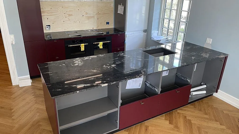 Poleret køkkenbordplade i Cosmic Black granit med køkkenø og bakre arbetsyta i ett køkken i Hellerup.