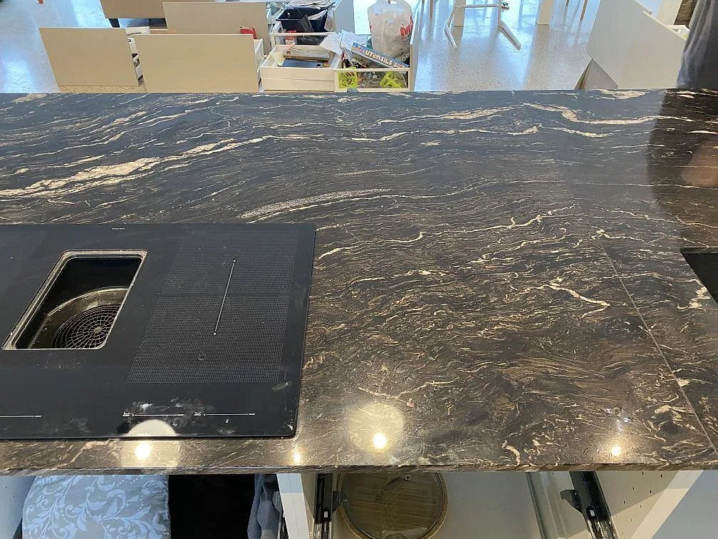 Køkkenbordplade i sort granit Cosmic Black, poleret, med underlimmad vask og infälld induktionshäll i ett køkken i Mörarp.