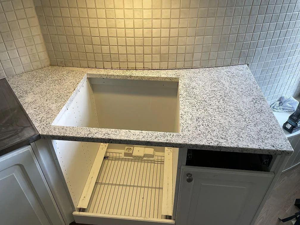 Køkkenbordplade i poleret Cotton White granit, 30 mm, med synlig öppning for underlimmad vask og vitt kakel i ett køkken i Stockholm.