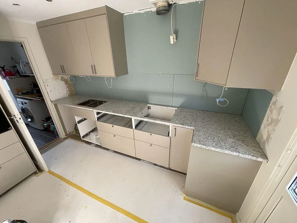 Køkkenbordplade i lys Cotton White granit, poleret, monteret som L-formad arbetsyta i ett køkken i Täby.