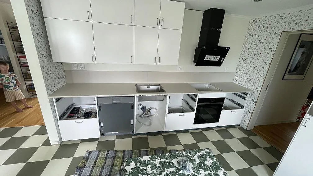 Køkkenbordplade i mat Dekton Aeris, lys keramik, med rostfri vask, hällurtag og låg stänkkant i ett køkken i Bara.