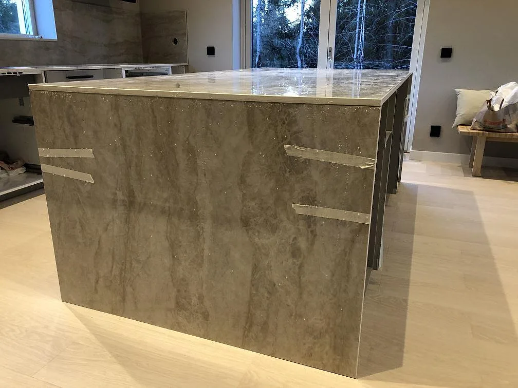 Køkkenø i Dekton Arga, poleret lys sten med blød åretegning, med hängande stensida i ett køkken med ekparkett i Borås.