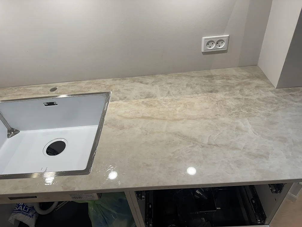 Køkkenbordplade i poleret Dekton Arga, lys keramik med marmorerad åretegning og synlig vask i ett køkken i Frederiksberg.