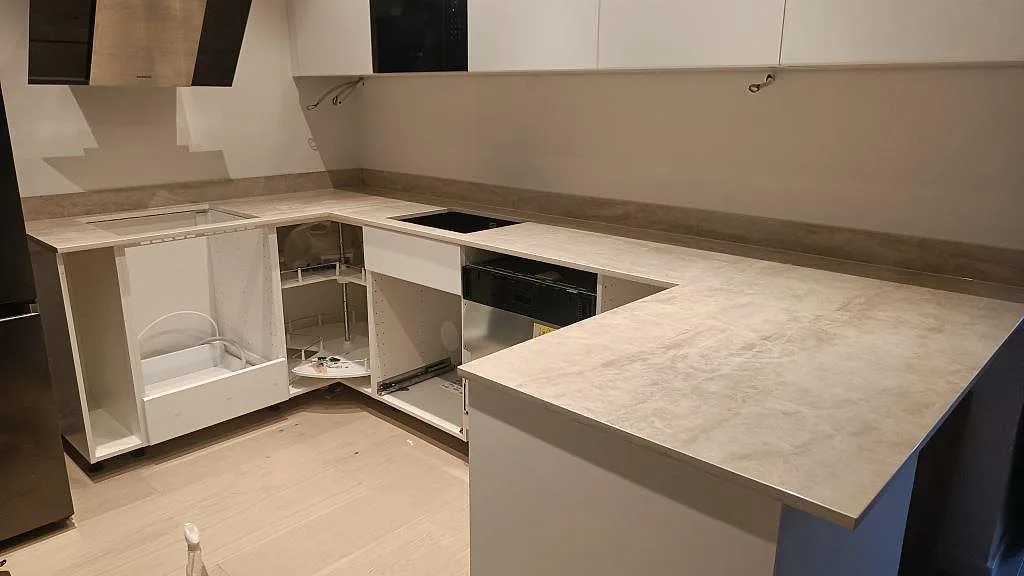 Køkkenbordplade i Dekton Arga, poleret lys marmorlik keramik, i ett L-format køkken med halvö og induktionshäll i Göteborg.