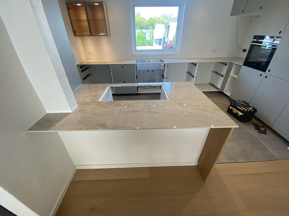 Översikt af køkkenbordplade i poleret Dekton Arga, 12 mm keramik, med bred arbetsyta og fönstersida i ett køkken i Greve.