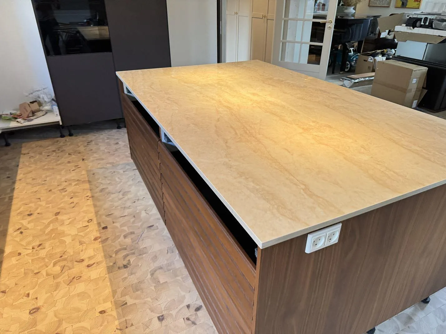 Bred köksyta i poleret Dekton Arga, cremebeige keramik med varm åretegning, på en köksdel i Greve.