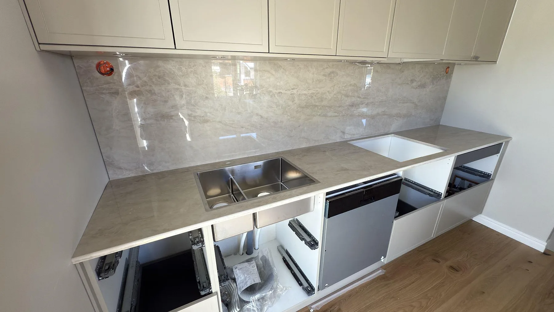 Køkkenbordplade i Dekton Arga, poleret keramik i cremebeige med marmorliknande åretegning, med underlimmad rostfri vask og heltäckande polerat stænkplade i ett køkken i Karlstad.