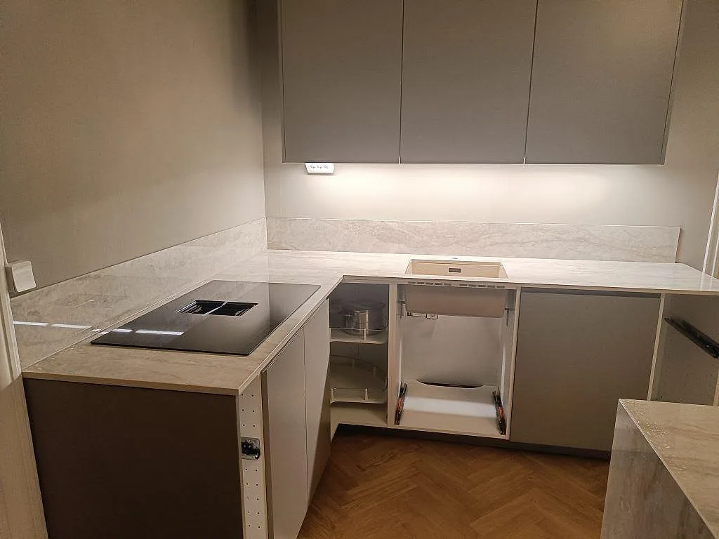Køkkenbordplade i hvid Dekton Arga, poleret, i ett U-format køkken i Malmö med övermonterad induktionshäll og underlimmad vask.
