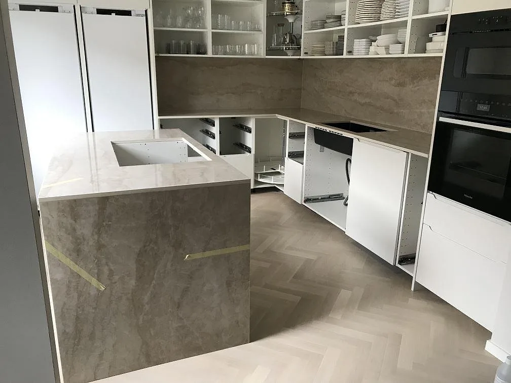 Køkkenbordplade i Dekton Arga, poleret keramik i marmorlook, i ett U-format køkken med køkkenø og heltäckande stænkplade i samme sten i Malmö.