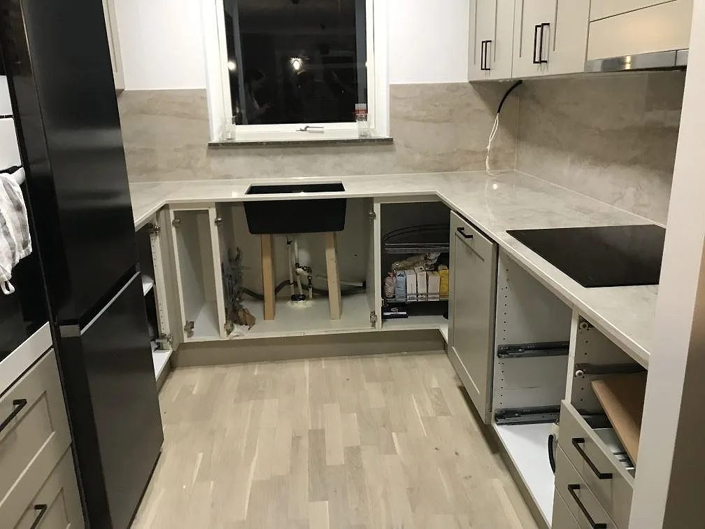 Køkkenbordplade i varmt cremebeige Dekton Arga, poleret, med matchande stænkplade i ett U format køkken under montering i Malmö.