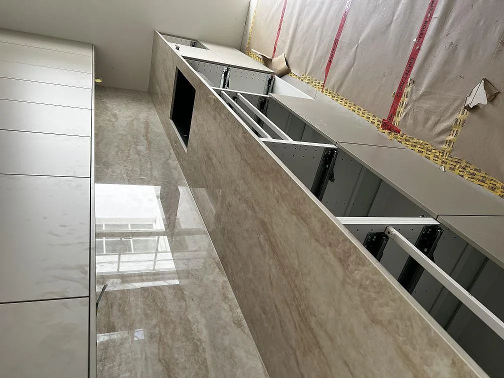 Køkkenbordplade i ljust gråmelerad Dekton Arga, poleret, med matchande vægbeklædning i ett halvfärdigt køkken i Malmö.