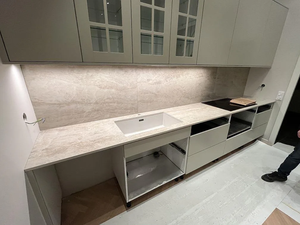 Køkkenbordplade i poleret beige Dekton Arga keramik med vask, hällzon og matchande stänkvägg i Segeltorp.
