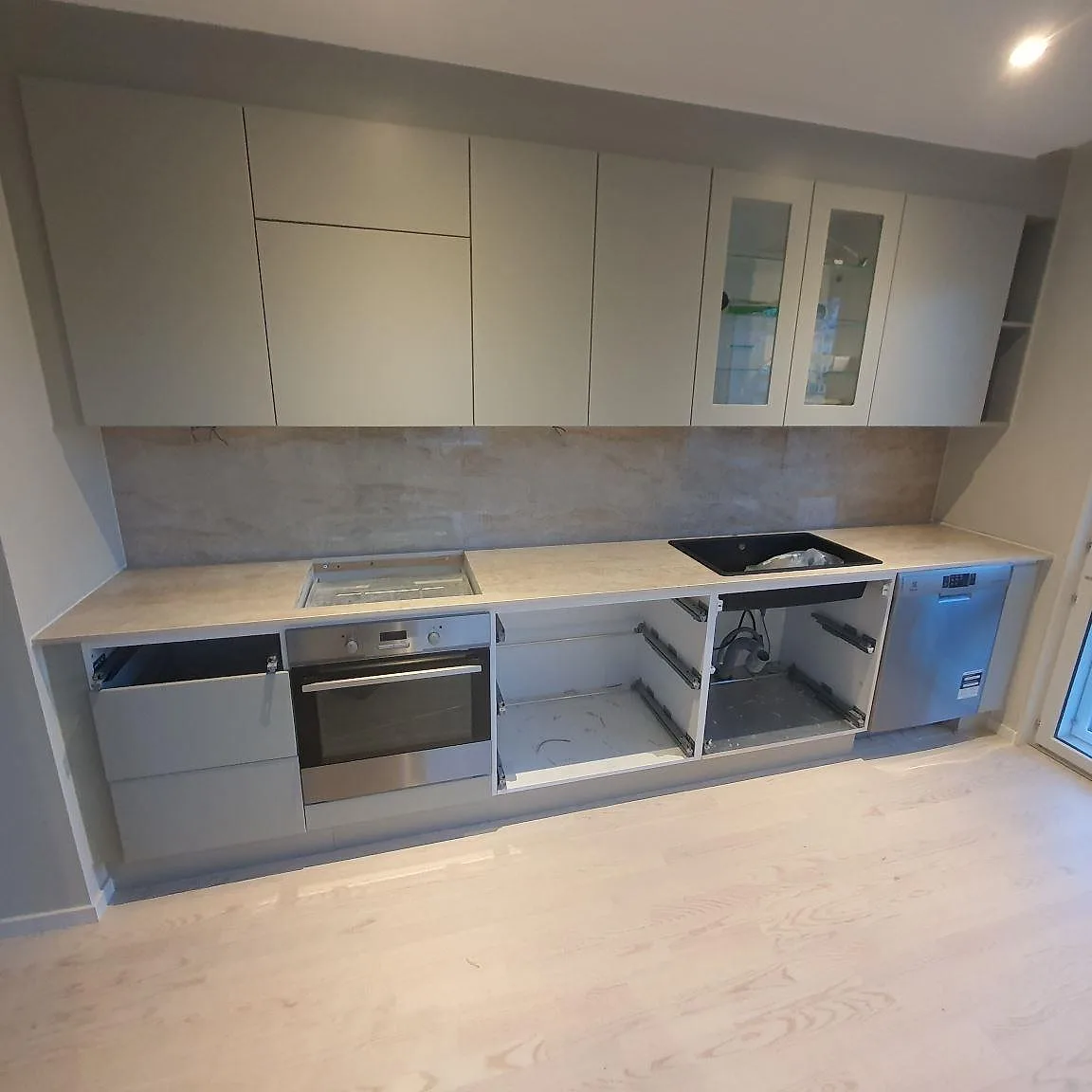 Køkkenbordplade i Dekton Arga keramik, poleret i varm cream, med matchande vægbeklædning i ett køkken under montering i Sollentuna.
