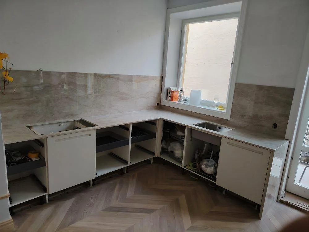 L-format køkken med køkkenbordplade og vægbeklædning i poleret Dekton Arga keramik, med marmorerad åretegning og synliga udskæring i Stockholm.