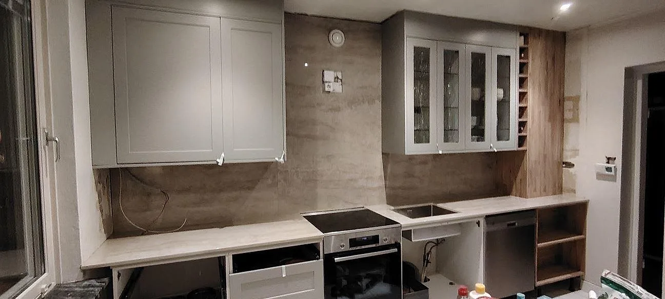 Køkkenbordplade i poleret Dekton Arga, 20 mm keramik, med matchande vægbeklædning i ett køkken under montering i Västerås.