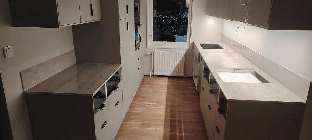 Poleret køkkenbordplade i Dekton Arga med lys åretegning, stænkplade og öppna köksstommar under montering i Valbo.