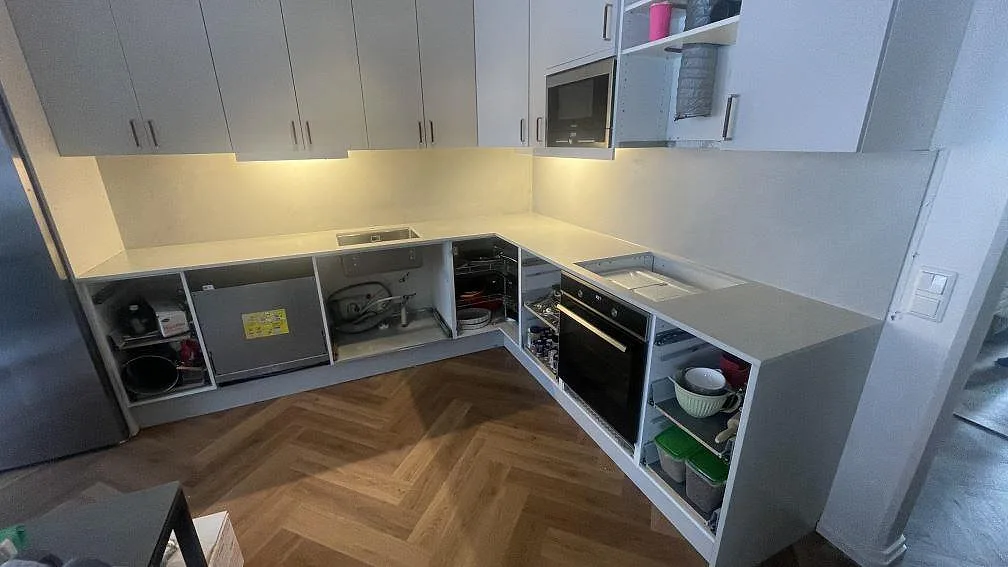 L-format køkken i Lund med mat keramikbordplade i Dekton Argentium og matchande stænkplade under montering.