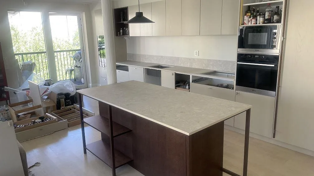 Køkkenbordplade og køkkenø i mat Dekton Ava med matchande låg stänkkant i ett køkken i Borås.