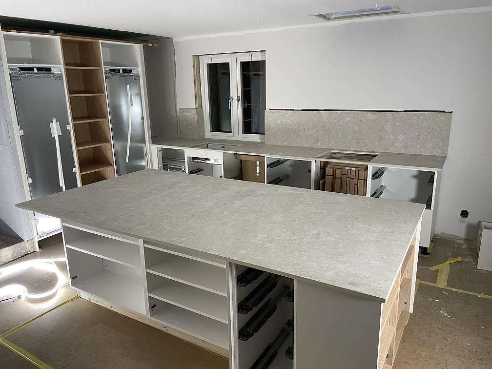 Køkkenbordplade og køkkenø i mat Dekton Ava i keramik i ett køkken under montering i Djurmo.
